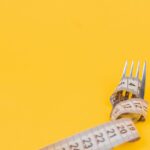 Fork with measuring tap wrapped around it on a yellow background
